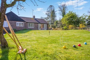 A grassy yard with a swing set, a brick house, and a clear sky. - 3 Bed in Berwick St. John (oc-k36615) (Berwick Saint John)
