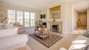A spacious living room with a fireplace, a large window, and a cozy seating area. - 3 Bed in Berwick St. John (oc-k36615) (Berwick Saint John)