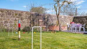 A grassy outdoor area with a stone wall, a wooden structure, and a table with chairs. - 3 Bed in Berwick St. John (oc-k36615) (Berwick Saint John)