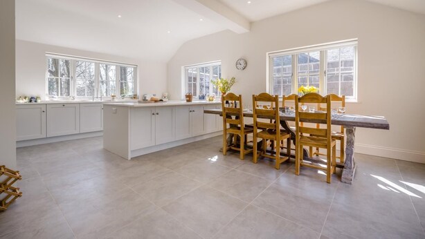 A spacious kitchen with a central island, wooden dining table, and large windows. - 3 Bed in Berwick St. John (oc-k36615) (Berwick Saint John)