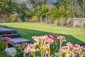 A well-maintained lawn with a stone pathway leading to a seating area, surrounded by lush greenery and trees. - 3 Bed in Berwick St. John (oc-k36615) (Berwick Saint John)