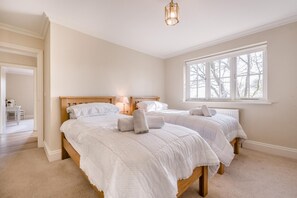 A bedroom with two beds, a window, and a lamp.