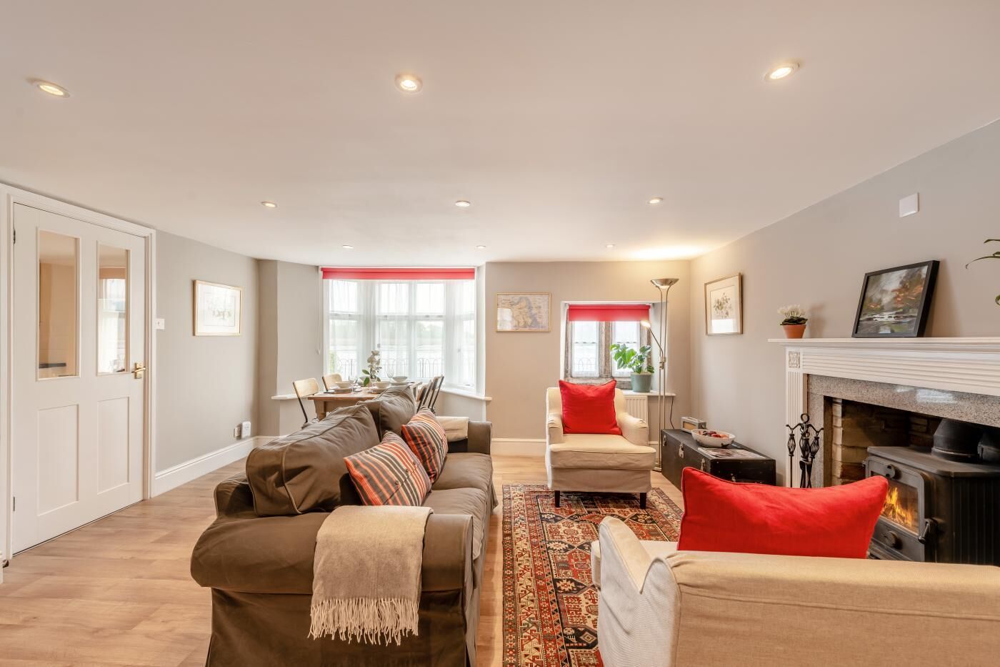 A living room with a sofa, armchairs, a fireplace, and a dining area with a table and chairs.
