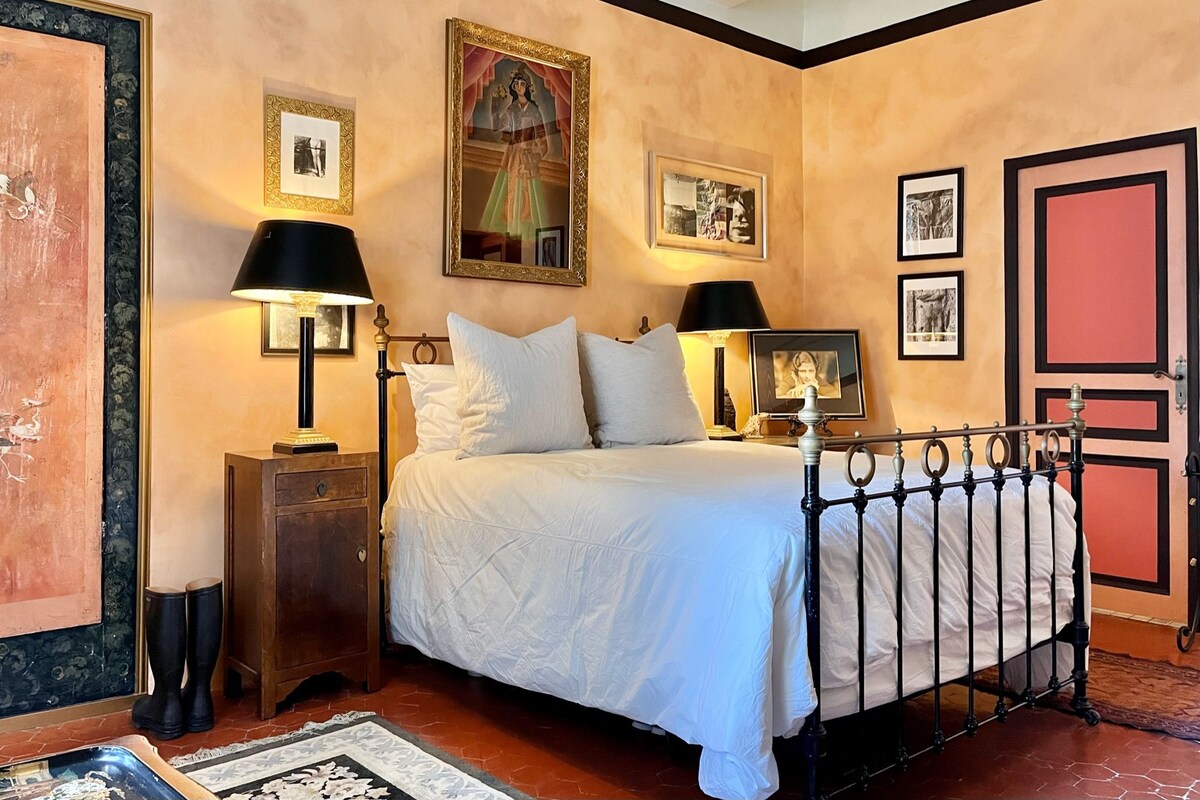 A bedroom with a bed, two bedside lamps, a nightstand, a dresser, and a door.
