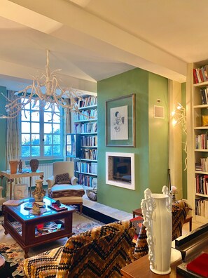 A cozy living room with a fireplace, a bookshelf, and a comfortable seating area. - La Maison des Chapitres (FORCALQUIER)