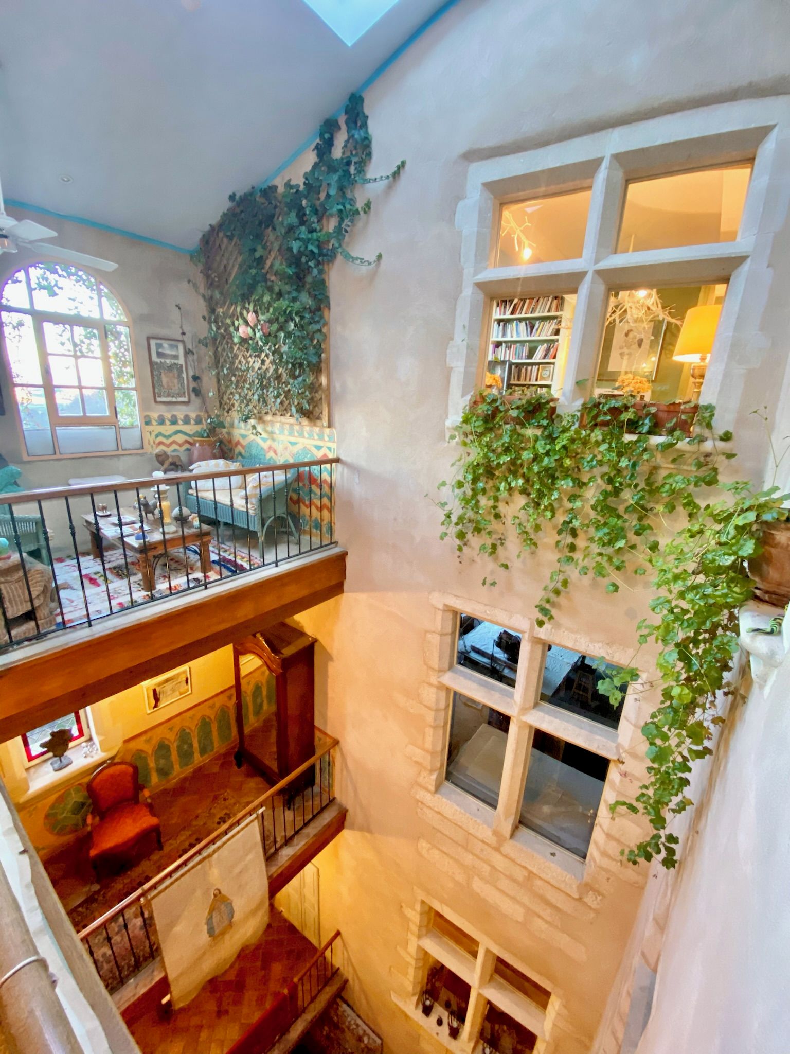 A multi-level interior with a balcony, a staircase, and a library.