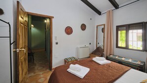 A bedroom with a large bed, a wooden door, a radiator, and a window with curtains.