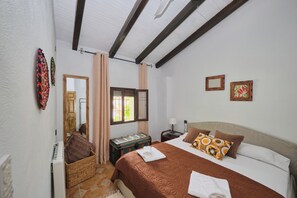 A bedroom with a bed, a nightstand, a dresser, a mirror, and a window with curtains. - Vrbo Property (Fornes)