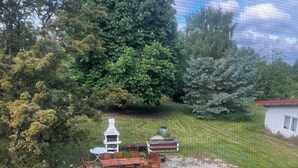 Eine Terrasse mit Tisch und Stühlen, umgeben von Bäumen und einem kleinen Gebäude.