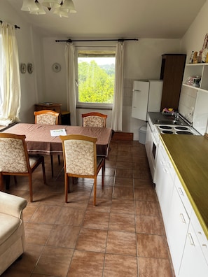 Una cocina compacta con estufa, lavamanos y una zona de comedor con mesa y sillas.