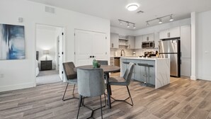 Une cuisine moderne dotée d’un îlot central, d’appareils électroménagers intégrés et d’un coin repas avec des chaises grises.