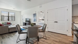 Un salon moderne comprenant un canapé, une table à manger avec des chaises et un coin cuisine avec des placards et un plan de travail.