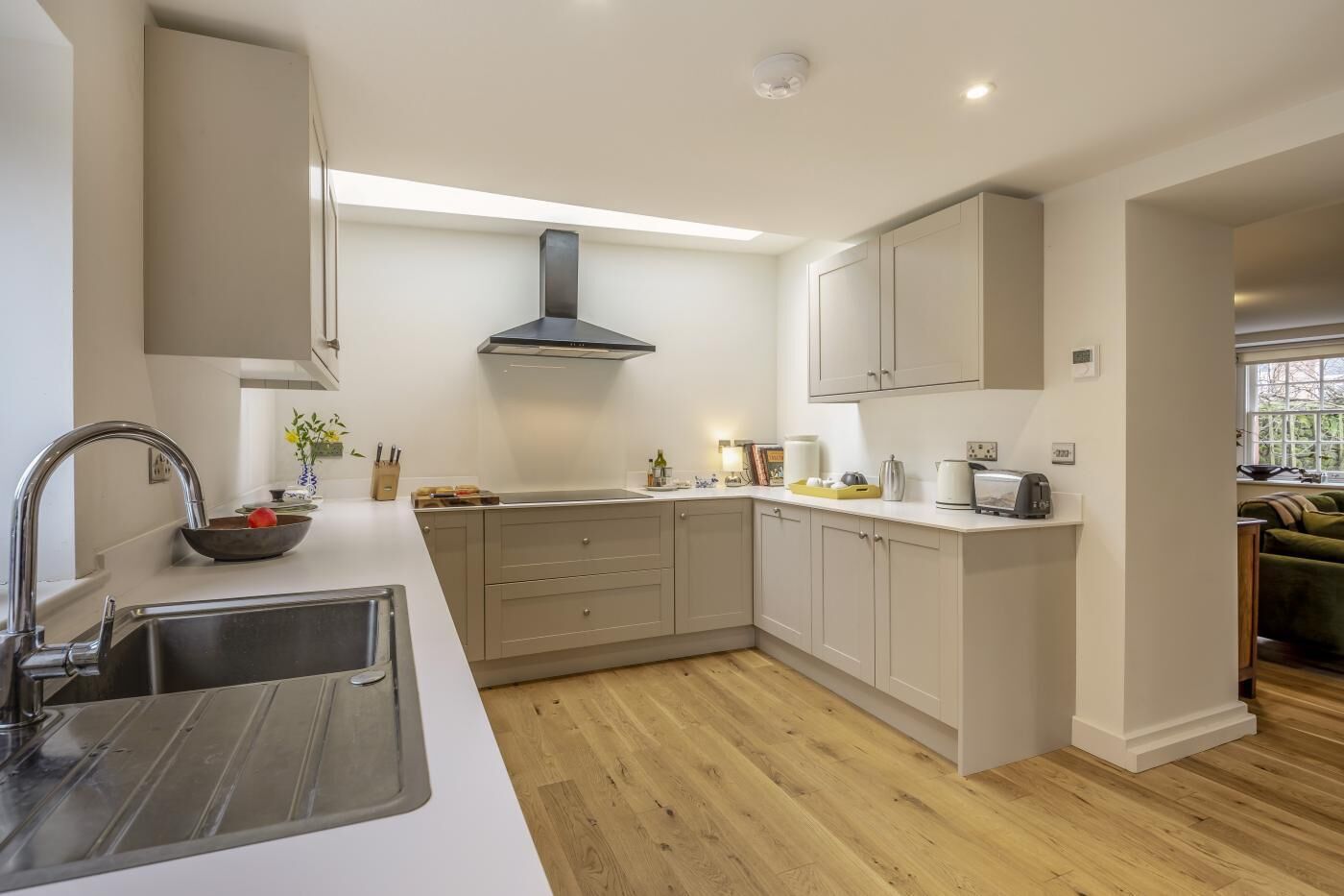 A modern kitchen with a stainless steel sink, a built-in stove, and light-colored cabinetry.
