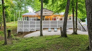Un chalet doté d’une terrasse, de meubles de jardin et d’un escalier menant à une zone abritée.