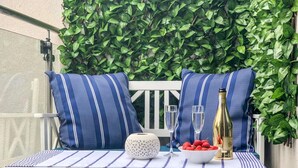 A white outdoor seating area with striped cushions, a bottle of champagne, glasses, and a bowl of strawberries. - 2 Bed in Alnwick (oc-coq92) (Alnwick)