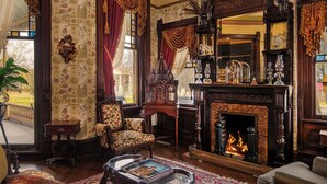 Una habitación tradicional con chimenea, muebles ornamentados y un espejo grande.