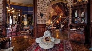 Une vaste pièce comprenant un grand fauteuil, un escalier et un buffet en bois orné d’objets décoratifs.