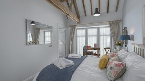 Ein Schlafzimmer mit einem Bett, einem Nachttisch, einer Lampe, einem Spiegel und einem Bücherregal.