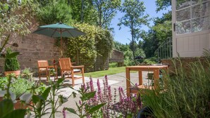 Eine Terrasse mit Tisch und Stühlen, umgeben von Topfpflanzen und Blumen.