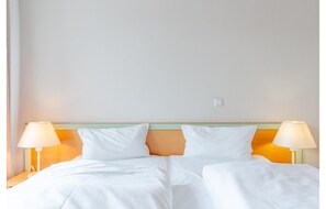 A hotel room with a double bed, two bedside lamps, and a plain wall. - Komfortable Ferienwohnung auf Rugen (Sellin)