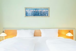 A double bed with white linens, two bedside lamps, and a painting above the bed. - Ferienwohnung Nahe Strand in Sellin (Sellin)