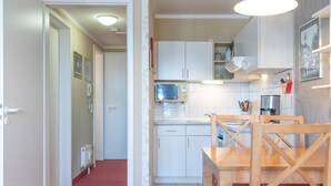 Una cucina funzionale con mobili bianchi, un forno a microonde e un tavolo da pranzo con sedie di legno.