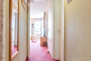 A hallway with a red carpet, wooden doors, and a small table with a chair in the distance. - Perfekt fur Familien - Ferienwohnung mit Balkon in Sellin (Sellin)