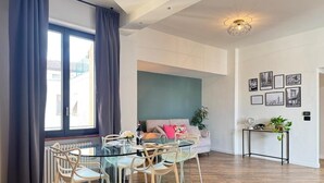 Ein modernes Wohnzimmer mit einem Glastisch, weißen Stühlen, einer Couch und einem Couchtisch.