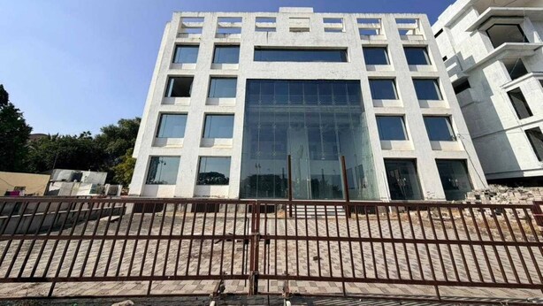 A modern building with multiple floors, large windows, and a central glass facade. - Palette Hotel and Resort Pandharpur (Pandharpur)