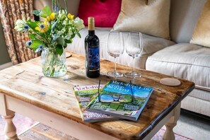 A wooden table with a bottle of wine, two glasses, a magazine, and a vase of flowers. - 4 Bed in Norwood (oc-b35549) (Norwood)