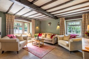 A cozy living room with a high ceiling, exposed beams, and large windows with patterned curtains. - 4 Bed in Norwood (oc-b35549) (Norwood)
