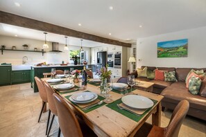 A modern kitchen with a dining area set for a meal, a sofa, and a painting on the wall. - 4 Bed in Norwood (oc-b35549) (Norwood)