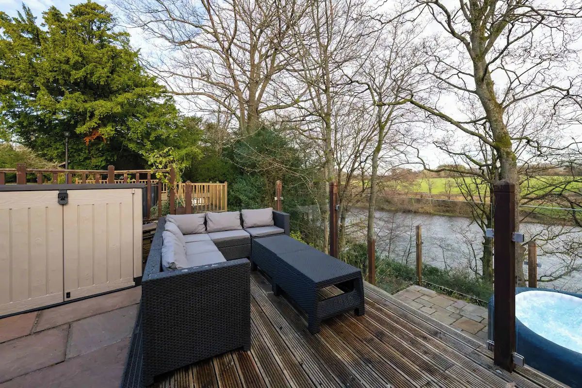 An outdoor deck with a sofa and a hot tub.