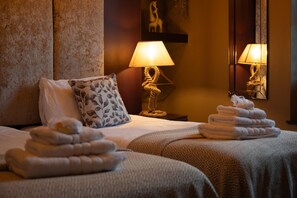 A hotel room with two beds, a nightstand with a lamp, and a wall-mounted mirror. - 7 Bed in Kendal (oc-t36284) (Kendal)
