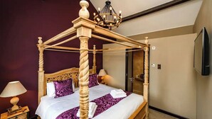 Una cama con dosel, una lámpara de noche y un espejo en la pared.