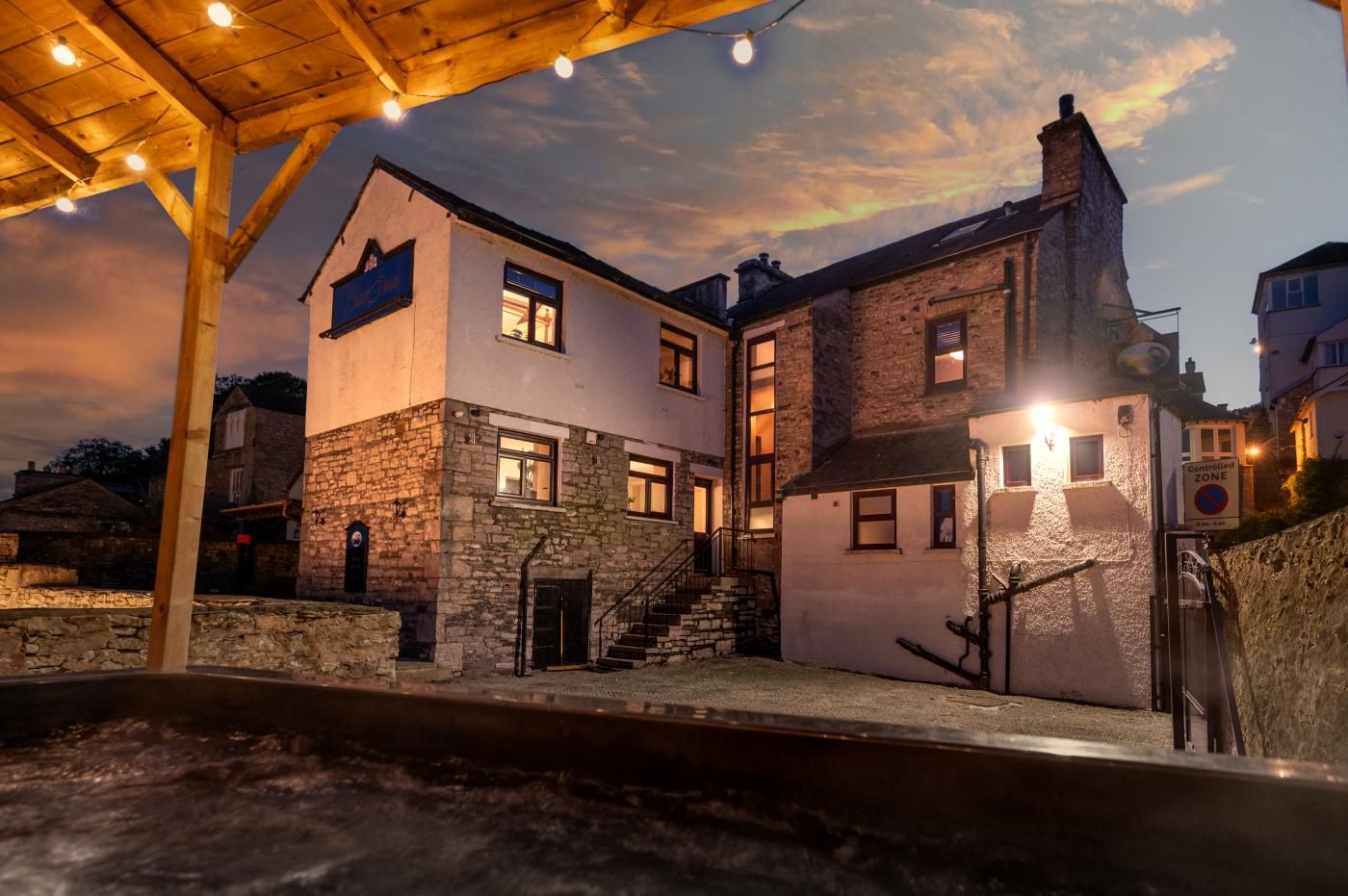 A two-story building with a stone facade, a wooden porch, and a staircase leading to the entrance.