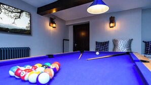 Una mesa de billar con bolas, techo azul e iluminación en la pared.