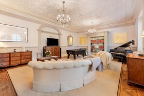 A spacious living room with a large, curved sofa, a grand piano, a pool table, and a television. - 2 Bed in Crook O Lune (oc-r36290) (Halton)