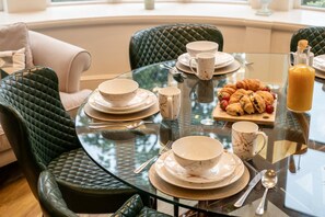 A dining table set with plates, bowls, and a tray of pastries, surrounded by upholstered chairs. - 2 Bed in Crook O Lune (oc-r36290) (Halton)