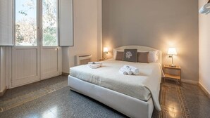 Een slaapkamer met een groot bed, twee bedlampen, een raam met zonwering en een deur.