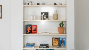 Een boekenplank met boeken, een ingelijst foto, een vaas en een potplant.