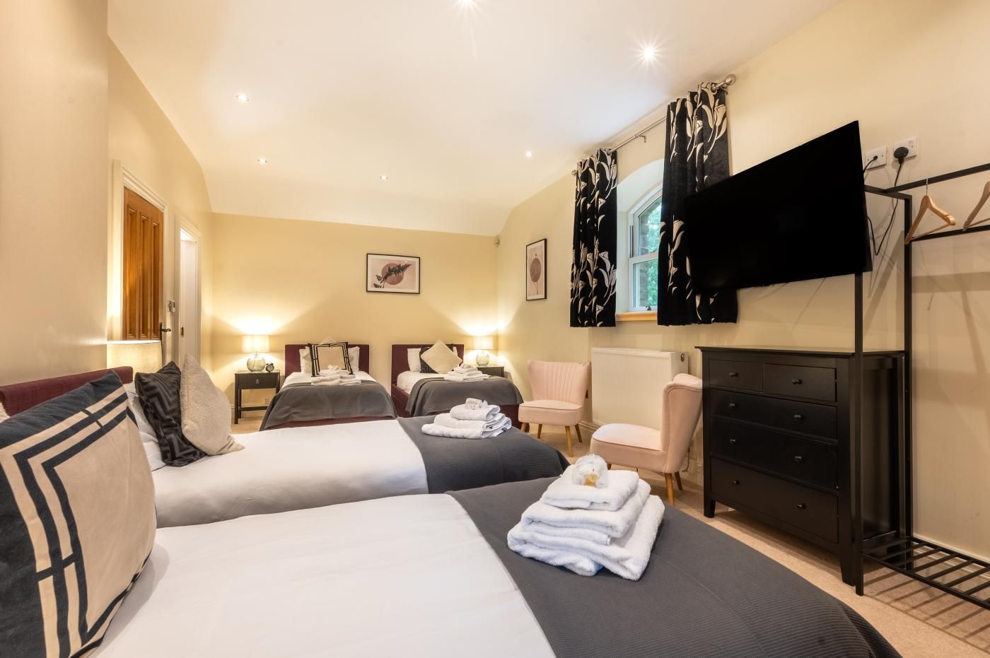 A hotel room with two beds, a television, a dresser, and a chair.