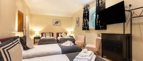 Ein Hotelzimmer mit zwei Betten, einem Fernseher, einem Schminktisch und einem Stuhl.