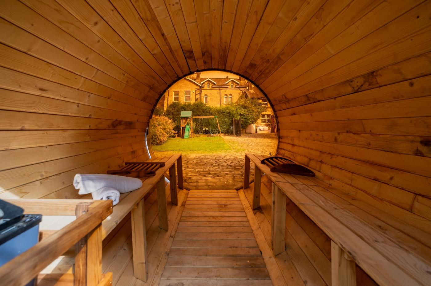 A wooden sauna with benches and a view of a building in the background.