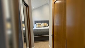 A bedroom with a bed, a wooden door, and a hallway leading to another room. - 2 Bed in Troutbeck Bridge (oc-p36885) (Troutbeck Bridge)