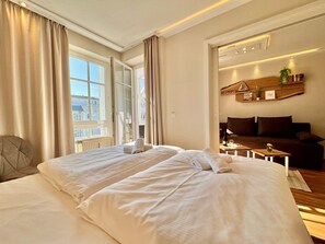 Une chambre d’hôtel avec un grand lit, un canapé, une petite table et une fenêtre avec des rideaux.