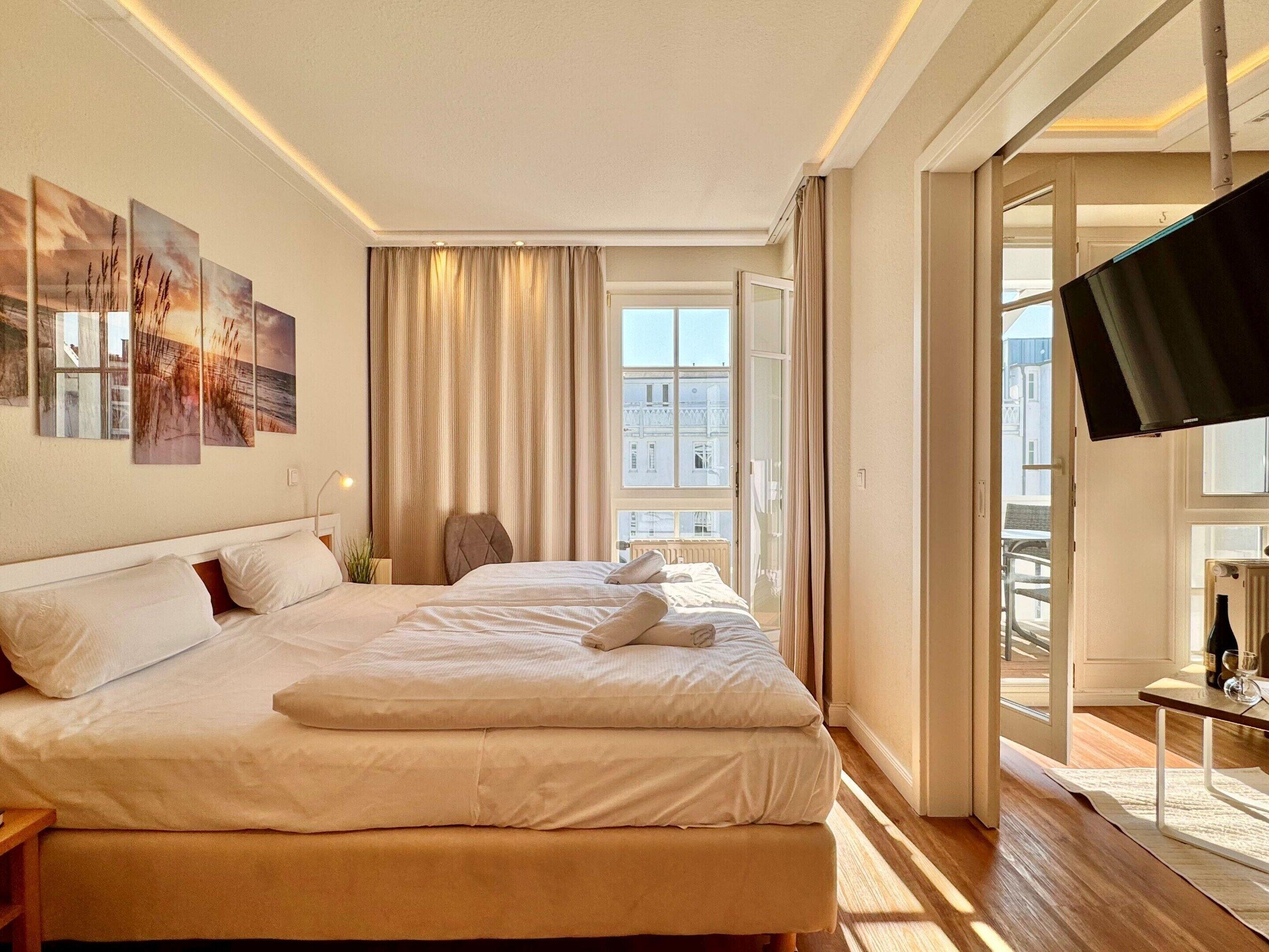 Habitación de hotel con cama, una silla, televisión y vistas a edificios.