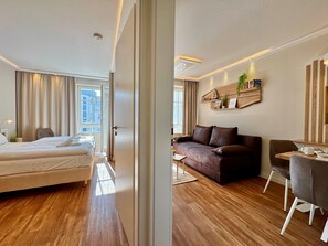 A hotel room with a bed, a sofa, a desk, and a chair. - Ferienwohnung in Sellin mit Balkon in Sudostlage (Sellin)