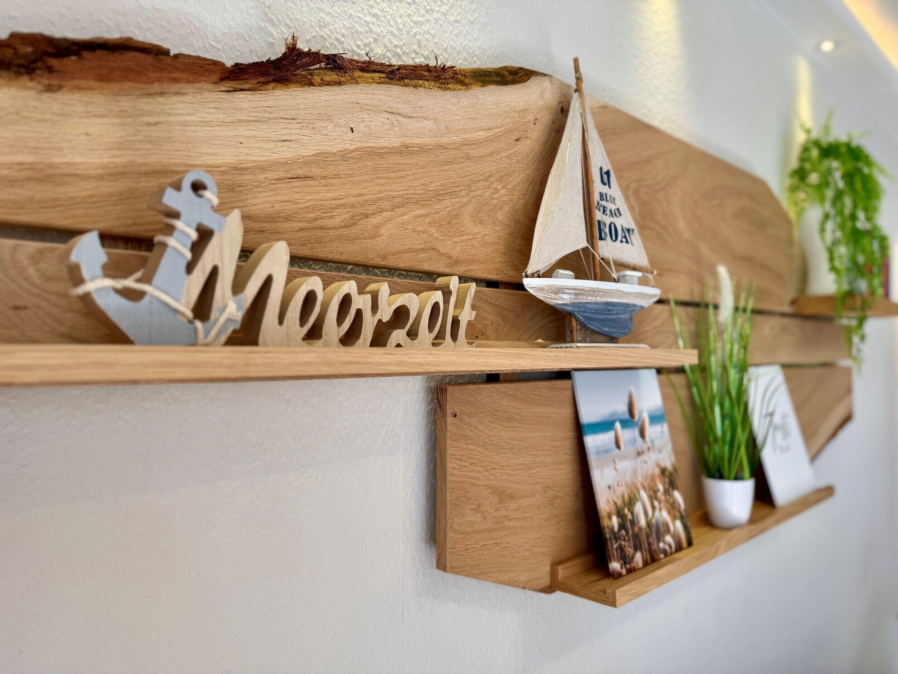 Una estantería de madera con un modelo de velero, una placa con nombre y un cuadro enmarcado.