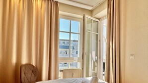 Ein Hotelzimmer mit Bett, Sessel und einem Fenster mit Vorhängen.